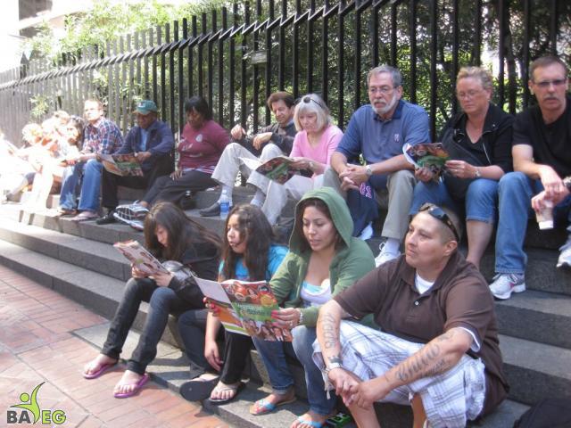 Waiting for the parade and reading a VSK from pre-parade leafleting by Ann, Katherine, Mila, Reeba and Tammy